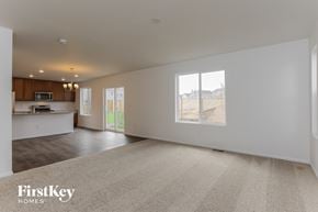 Colorado Springs house for rent - A spacious living room with a carpeted floor and a large window overlooking a barren landscape.