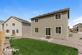 Colorado Springs house for rent - A house with a brown roof and a grey siding is shown with a grassy area in front.