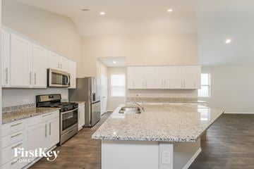 Conroe house for rent - A kitchen with white cabinets and a granite countertop.