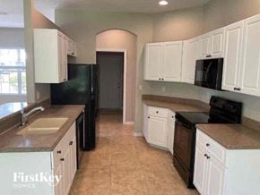 North Port house for rent - a kitchen with white cabinets and a black refrigerator