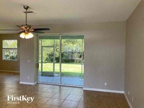 North Port house for rent - an empty living room with a ceiling fan and a sliding glass door