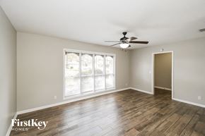 Jacksonville house for rent - an empty living room with a ceiling fan and a large window