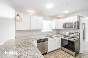 Jacksonville house for rent - a kitchen with white cabinets and a marble counter top