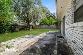 Jacksonville house for rent - a backyard with a white brick wall and a lawn and trees