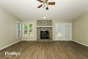 Greenwood house for rent - A spacious room with a fireplace and a ceiling fan.