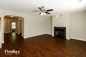 Greensboro house for rent - A spacious living room with a fireplace and a ceiling fan.