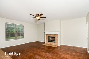Melissa house for rent - A spacious room with a fireplace and a ceiling fan.