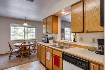 Spokane apartment for rent - A kitchen with wooden cabinets and a dining table with chairs.
