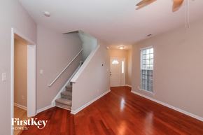 Monroe house for rent - A spacious room with wooden floors and a staircase leading to the upper level.