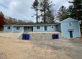 Bolton apartment for rent - A blue house with a grey roof and two blue bins in front.