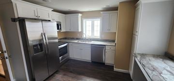 Bolton apartment for rent - A kitchen with a stainless steel refrigerator and white cabinets.