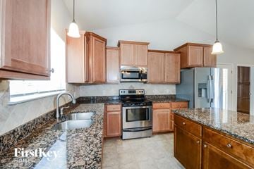 Wentzville house for rent - A kitchen with wooden cabinets and granite countertops.