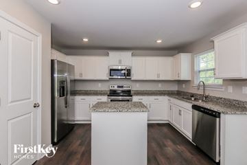 Charlotte house for rent - a kitchen with white cabinets and granite counter tops