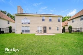 Atlanta house for rent - a yellow house with a grassy yard and a black fence