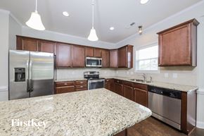 Lewisville house for rent - a kitchen with wooden cabinets and granite counter tops and stainless steel appliances