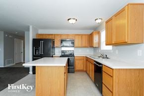 Indianapolis house for rent - a large kitchen with wooden cabinets and black appliances