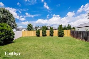 Monroe house for rent - the backyard of a house with a wooden fence and grass and trees