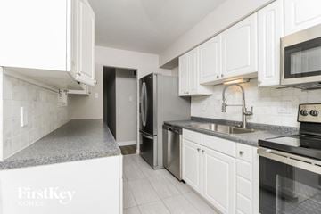 Kirkwood house for rent - a kitchen with white cabinets and stainless steel appliances