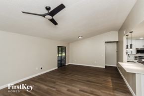 Palm Bay house for rent - A spacious room with a fan and a kitchen area in the background.