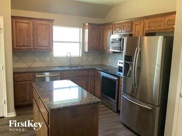 Rhome house for rent - a kitchen with wooden cabinets and stainless steel appliances