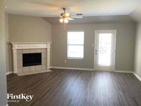 Rhome house for rent - an empty living room with a fireplace and a ceiling fan