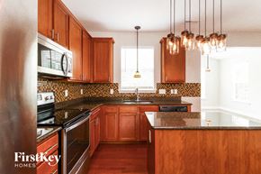 Clemmons house for rent - a kitchen with wooden cabinets and black counter tops and a sink