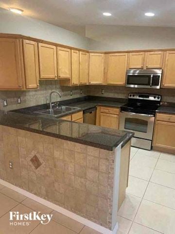 North Port house for rent - A kitchen with wooden cabinets and a black countertop.