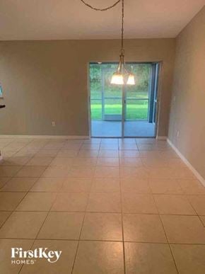 North Port house for rent - A room with a large tiled floor and a view of a green lawn through a sliding glass door.