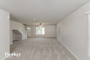 San Antonio house for rent - A spacious room with a carpeted floor and a staircase on the left side.