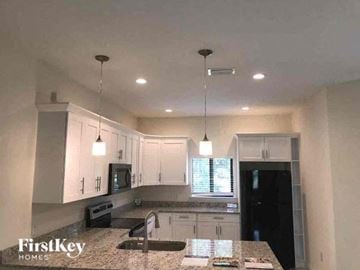 Lehigh Acres house for rent - a kitchen with white cabinets and a counter top