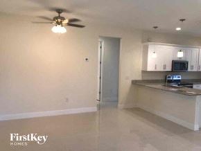 Lehigh Acres house for rent - an empty living room and kitchen with a ceiling fan