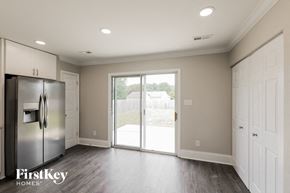 Indian Trail house for rent - A kitchen with a refrigerator, cabinets, and a sliding glass door leading to a backyard.