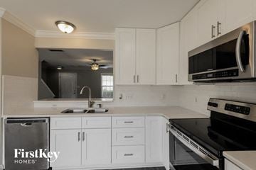 Indian Trail house for rent - A kitchen with white cabinets and black appliances.