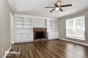 High Point house for rent - a living room with a fireplace and white shelves and a ceiling fan