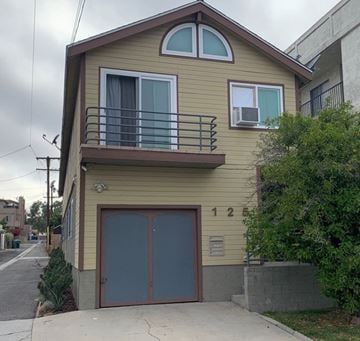 San Pedro apartment for rent - a yellow house with a balcony and a garage door