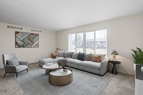 Madison Heights apartment for rent - A living room with a grey couch, a grey armchair, a coffee table, and a potted plant.