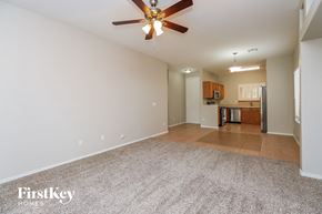 San Tan Valley house for rent - an empty living room with a ceiling fan and a kitchen