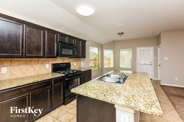 Fort Worth house for rent - A kitchen with granite countertops and dark brown cabinets.
