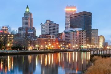 Providence apartment for rent - A cityscape at dusk with buildings reflecting in the water.