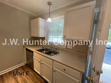Wilson apartment for rent - A kitchen with white cabinets and a sink is shown with the text "J.W. Hunter Company Inc." and "Unit E" on the image.