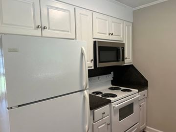 Wilson apartment for rent - A white refrigerator is in a kitchen with white cabinets and a black countertop.