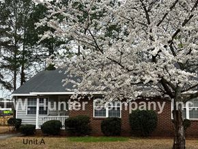 Wilson apartment for rent - A tree with white blossoms is in front of a brick building with a sign that says "TW Hunter Company Inc."