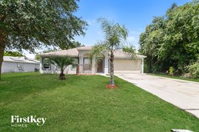 Poinciana house for rent - A well-maintained lawn in front of a house with a palm tree.