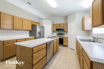 Poinciana house for rent - A kitchen with wooden cabinets and a refrigerator.