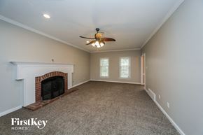Collierville house for rent - a living room with a fireplace and a ceiling fan