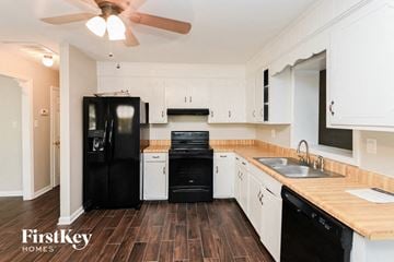 Charlotte house for rent - a kitchen with white cabinets and a black refrigerator