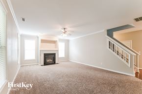 Fuquay Varina house for rent - A spacious living room with a fireplace and a staircase.
