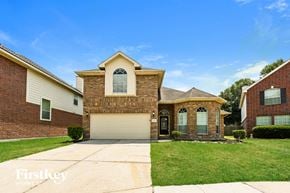 Humble house for rent - a brick house with a white garage door and a lawn