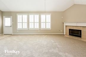 Humble house for rent - an empty living room with a fireplace and windows