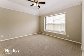 Humble house for rent - a bedroom with a large window and a ceiling fan